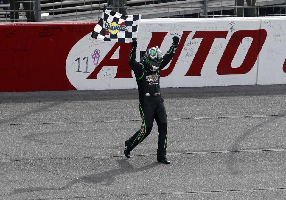 Kyle Busch (18) celebrates with the checkered flag after winning the NASCAR Sprint Series auto race in Fontana, Calif., Sunday, March 23, 2014. (AP Photo/Alex Gallardo)