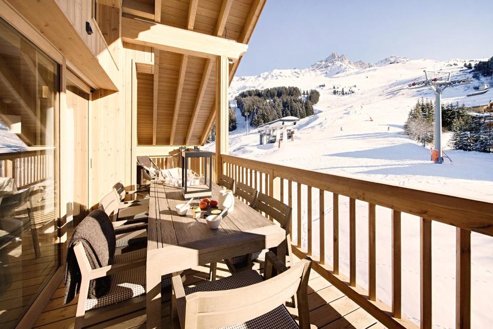 a deck with chairs and a table on it with snow on the side