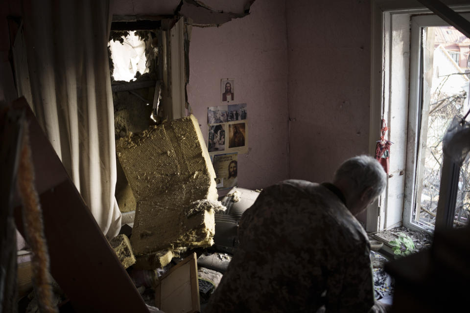 Anatolii Kaharlytskyi, 73, looks for his belongings inside his home, heavily damaged after a Russian attack in Kyiv, Ukraine, Monday, Jan. 2, 2023. Kaharlytskyi was injured and his daughter-in-law Iryna died in the attack on Dec. 31, 2022. (AP Photo/Renata Brito)