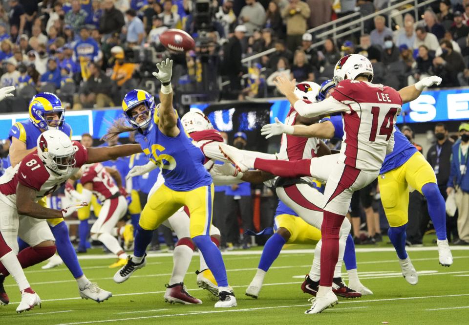 Jan 17, 2022; Los Angeles, California, USA;  Arizona Cardinals punter Andy Lee (14) punts the ball under pressure by Los Angeles Rams' Christian Rozeboom (56) during the first quarter of the NFC Wild Card playoff game.