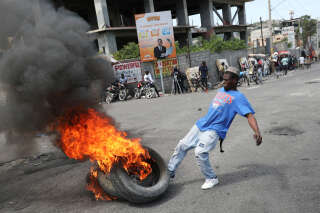Le 7 mars 2024, à Port-au-Prince (Haïti). Un homme met un coup de pied dans des pneus en feu, lors d’une manifestation causée par la prolongation de l’état d’urgence par le gouvernement. . PHOTO Ralph Tedy Erol/REUTERS