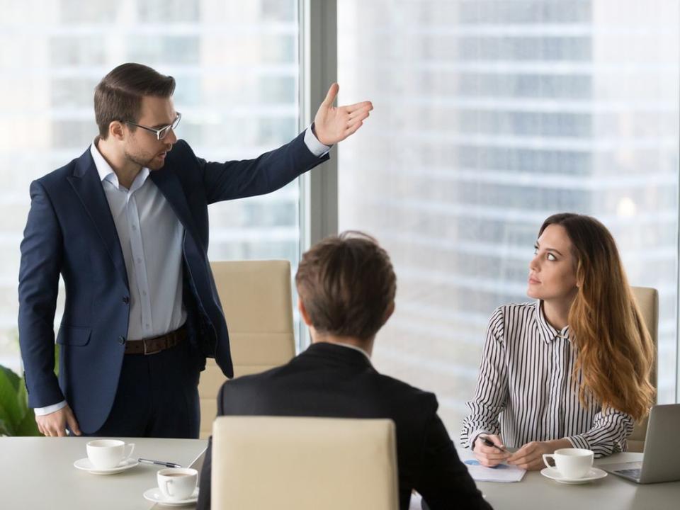 Mad male worker asking female partner leave meeting