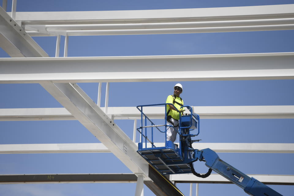 In this July 3, 2018, file photo, a construction worker lowers himself on a forklift at a construction site in Chicago. On Tuesday, Aug. 4, the Commerce Department reports on U.S. construction spending in July. (AP Photo/Annie Rice)