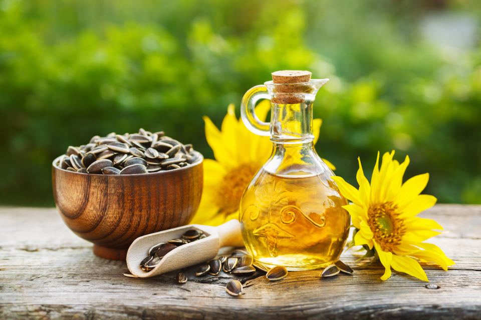 sunflower oil in a small glass jar with sunflower seeds and fresh flowers. 