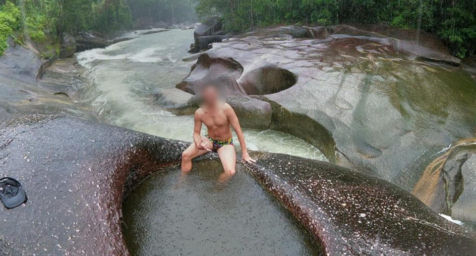 Man sitting on rock at Devil's Pool in Babinda Boulders, near Cairns. 