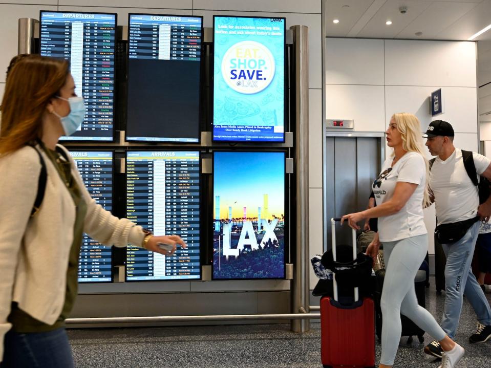 photo of some passengers walking through LAX masked, while others are not