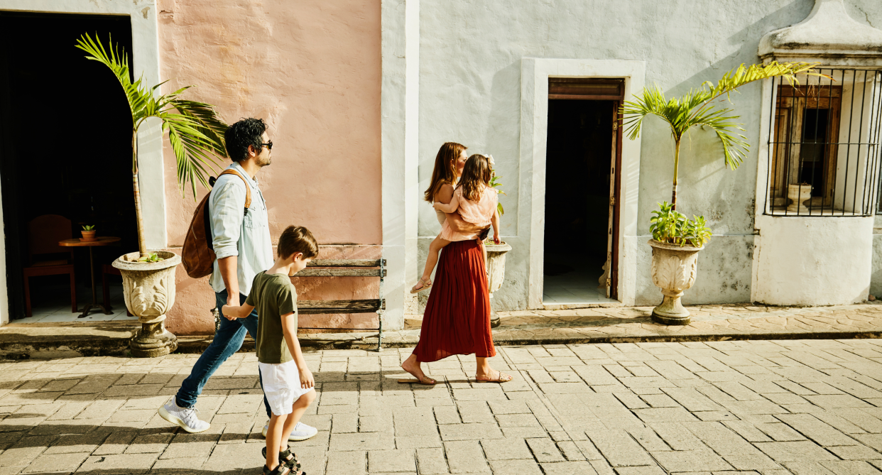 two parents walking with two children outside on sidewalk on vacation, labour day vacation travel deals canada