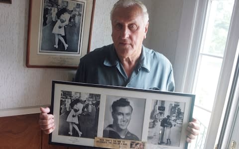 George Mendonsa poses for a photo in Middletown, R.I., holding a copy of the famous Alfred Eisenstadt photo of Mendonsa kissing a woman in a nurse's uniform in Times Square  - Credit: AP