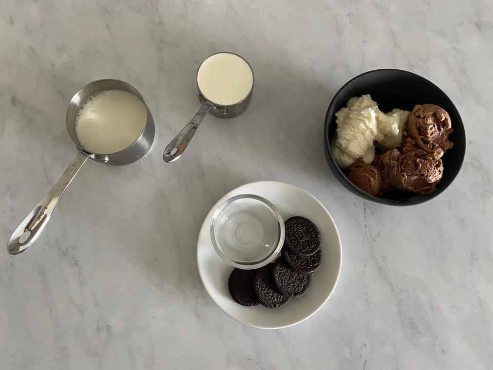 Flat lay of vanilla and chocolate ice cream, heavy cream, milk, and peppermint extract.