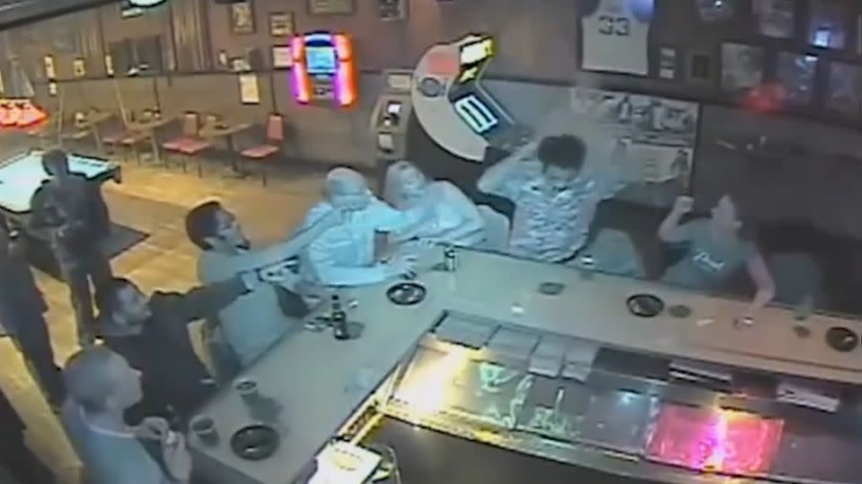 When other bar-goers point out that he is on fire, he acts quickly and pats the fire out. Photo: YouTube