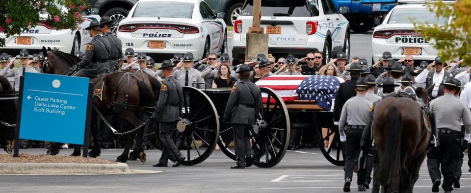 Officers salute as N.C. State Highway Patrols Caisson Unit passes them during a procession for slain Wake Sheriffs Deputy Ned Byrd before his funeral at Providence Baptist Church in Raleigh, N.C., Friday, August 19, 2022.