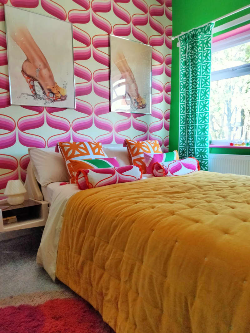 A pink wallpaper graphic with bed with yellow bedding.