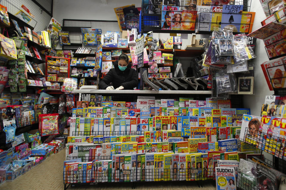 In this photo taken on Thursday, March 12, 2020, a shopkeeper wears a mask as she works in a bookshop in Codogno, Italy. The northern Italian town that recorded Italy’s first coronavirus infection has offered a virtuous example to fellow Italians, now facing an unprecedented nationwide lockdown, that by staying home, trends can reverse. Infections of the new virus have not stopped in Codogno, which still has registered the most of any of the 10 Lombardy towns Italy’s original red zone, but they have slowed. For most people, the new coronavirus causes only mild or moderate symptoms. For some it can cause more severe illness. (AP Photo/Antonio Calanni)