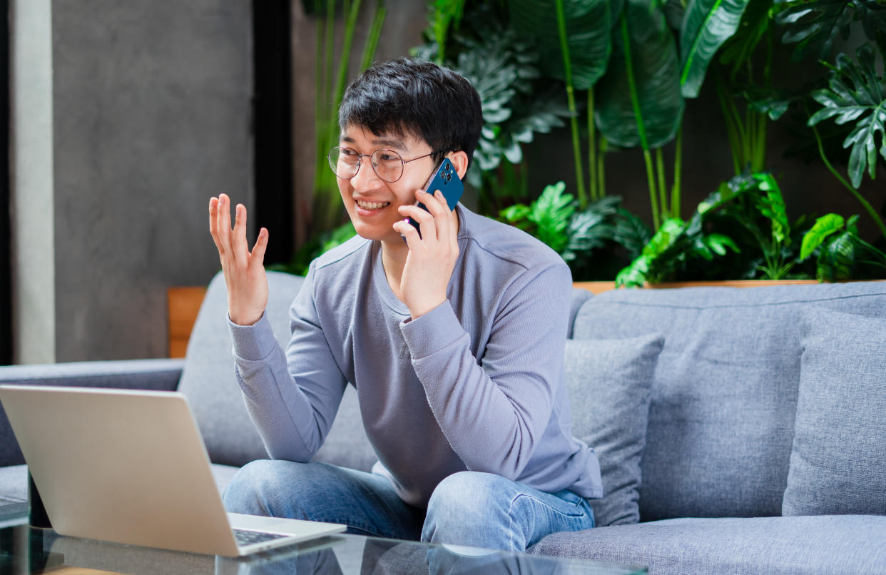 Young Asian businessman at home speaking on his cell phone