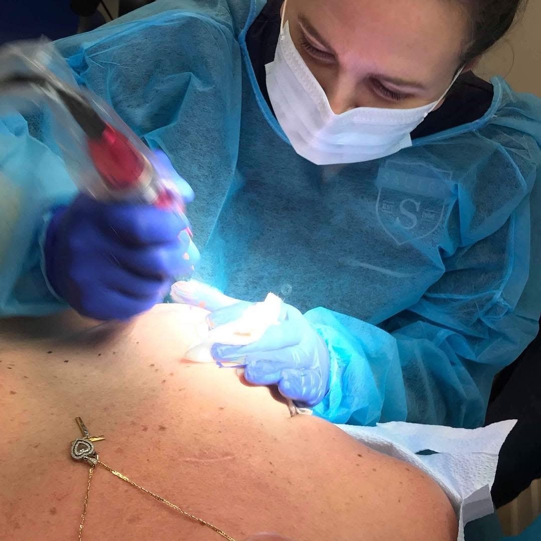 Jenean LaCorte helps a patient by putting a tattoo on their chest.