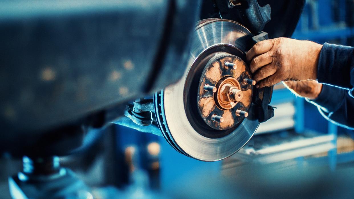 Closeup of unrecognizable mechanic replacing car brake pads.