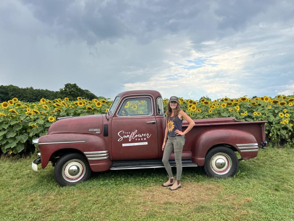 Woman stands in front of a vintage car at The Sunflower Farm in Durham Region