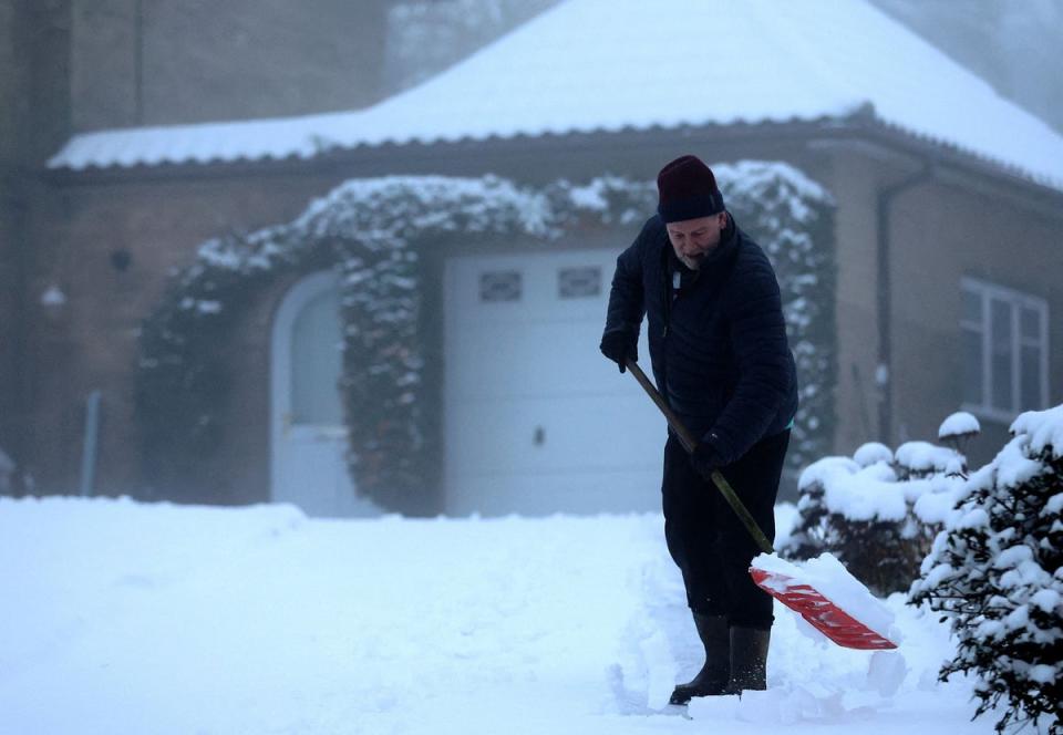 A man clears snow from his driveway, Keele, Staffordshire on Sunday (REUTERS)