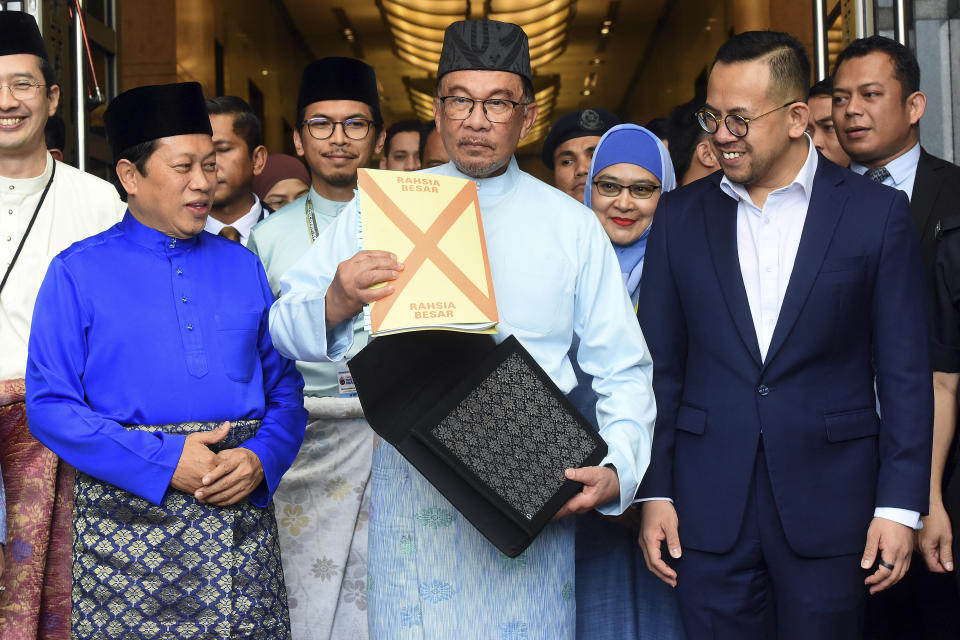 Malaysia's Prime Minister and Finance Minister Anwar Ibrahim, center, poses with a briefcase containing his 2023 budget speech as he leaves the Finance Ministry building for the Parliament in Putrajaya, Malaysia, Friday, Feb. 24, 2023. (AP Photo)