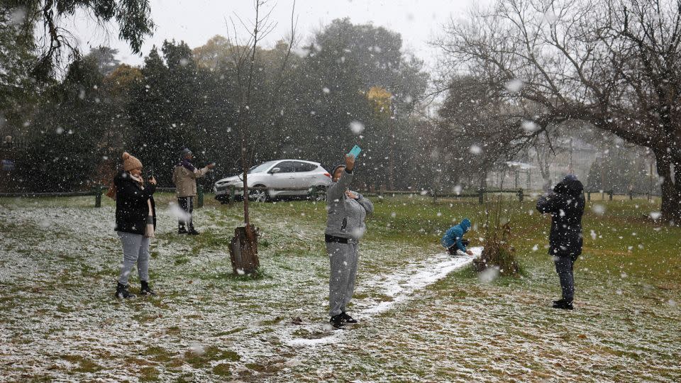 People take photos as snow falls in Zoo Lake park in Johannesburg on July 10. - Wikus de Wet/AFP/Getty Images