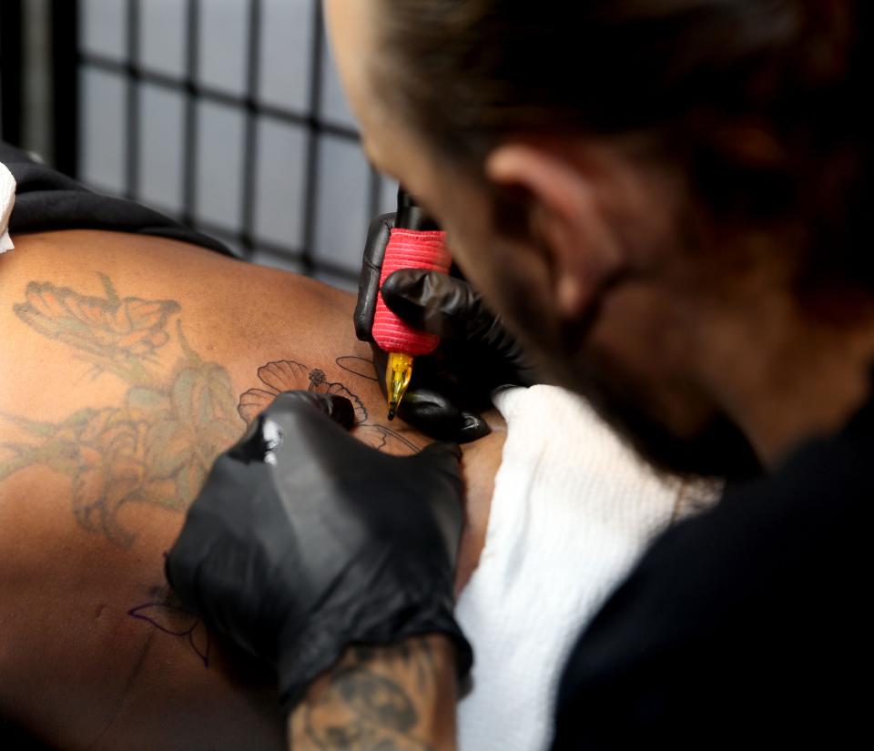 Tatoo artist Kustom does touch ups on a client at Black Ink.