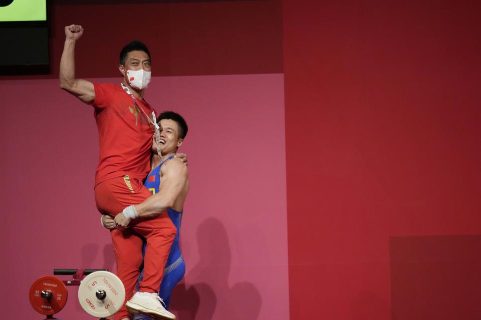 Lyu Xiaojun of China celebrates with his coach after winning the gold medal in the men's 81kg weightlifting event, at the 2020 Summer Olympics, Saturday, July 31, 2021, in Tokyo, Japan. (AP Photo/Luca Bruno)