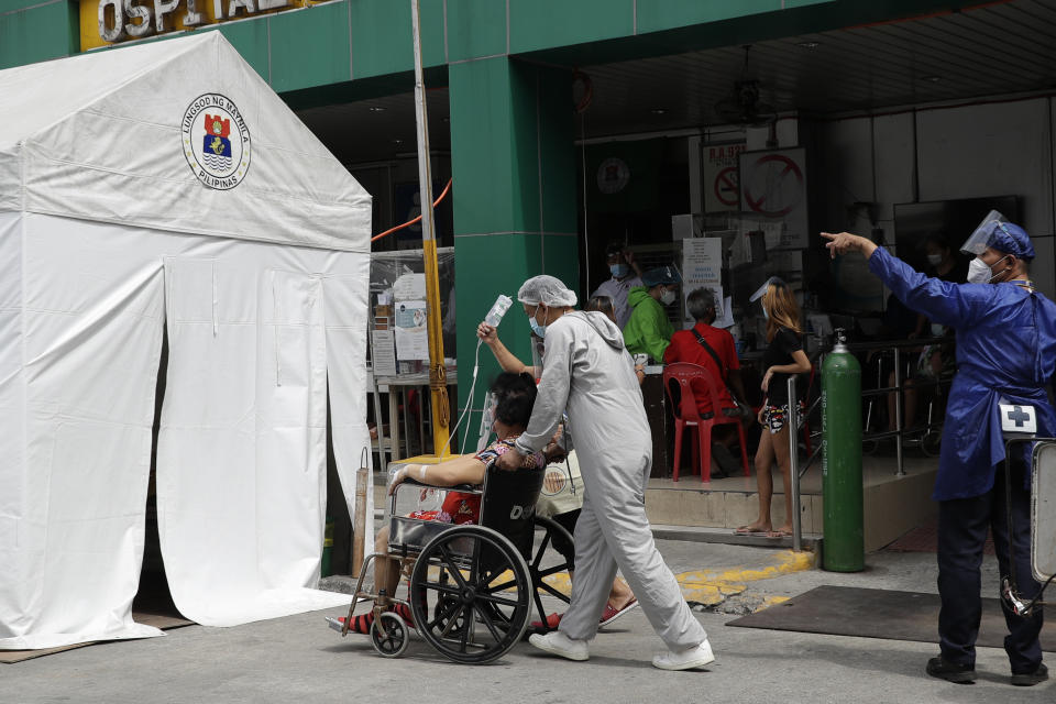 A health worker wearing a protective suit pushes a COVID-19 patient to an isolation tent outside a hospital in Manila, Philippines on Monday, April 26, 2021. COVID-19 infections in the Philippines surged past 1 million Monday in the latest grim milestone as officials assessed whether to extend a monthlong lockdown in Manila and outlying provinces amid a deadly spike or relax it to fight recession, joblessness and hunger. (AP Photo/Aaron Favila)