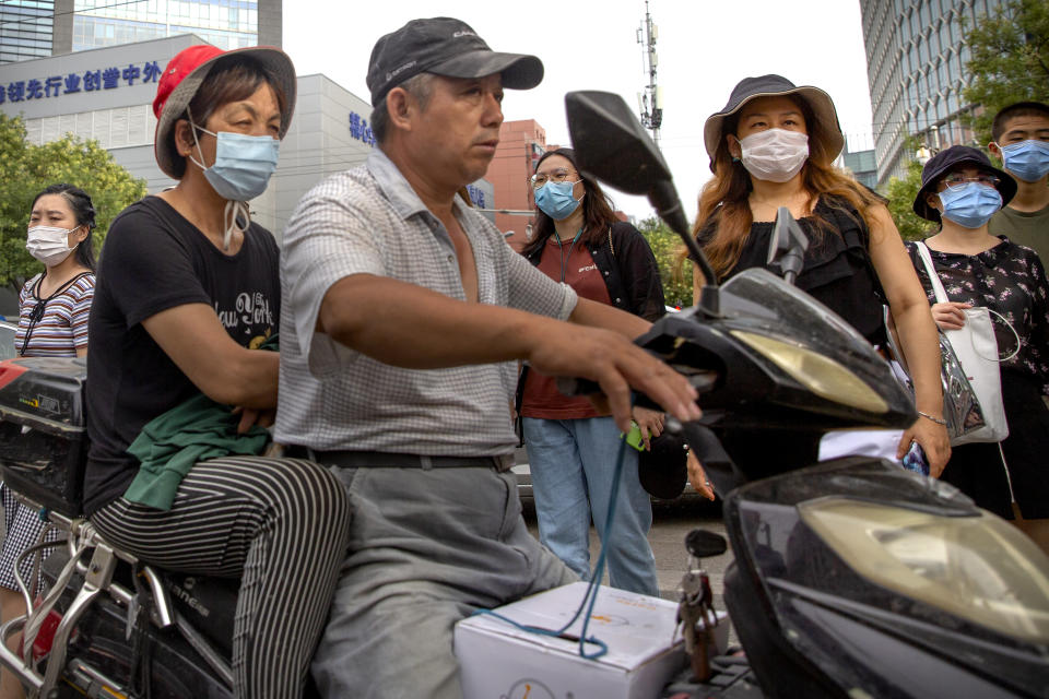 People wearing face masks to protect against the coronavirus wait to cross an intersection in Beijing, Saturday, July 25, 2020. China on Saturday reported several dozen new confirmed coronavirus cases, including a few who caught the virus abroad. (AP Photo/Mark Schiefelbein)