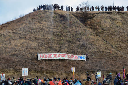 FILE PHOTO -- Protesters raise a banner on Turtle Island on Thanksgiving day during a protest against plans to pass the Dakota Access pipeline near the Standing Rock Indian Reservation, near Cannon Ball, North Dakota, U.S. November 24, 2016. REUTERS/Stephanie Keith/File Photo