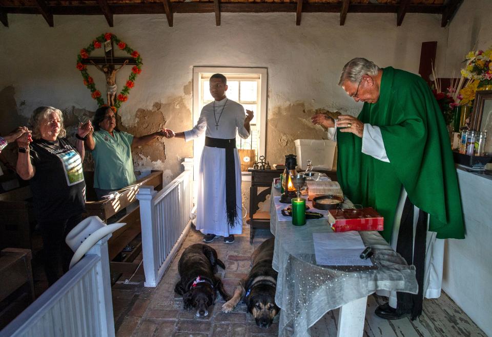 Fr. Roy Snipes says mass at La Lomita Chapel while his dogs, Charlotte, left and Bandito, right, lay on the brick floor. The chapel is at the center of a religious freedom lawsuit against the Federal government. The proposed border wall will cut off access to the site on the Rio Grande River. Sept. 17, 2019