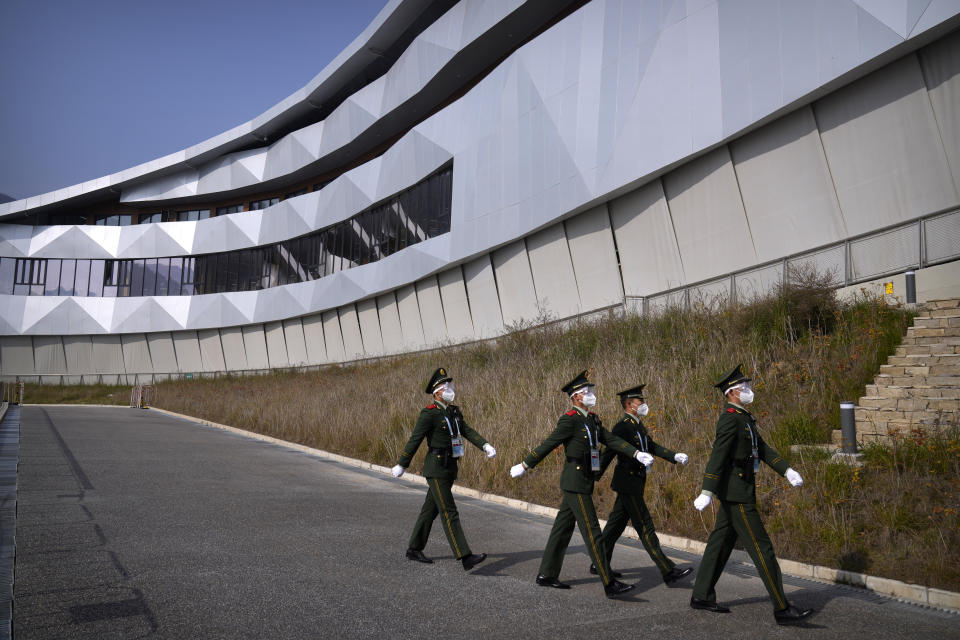 Chinese paramilitary police wearing goggles and face masks march in formation at the Yanqing National Sliding Center during an IBSF sanctioned race, a test event for the 2022 Winter Olympics, in Beijing, Monday, Oct. 25, 2021. A northwestern Chinese province heavily dependent on tourism closed all tourist sites Monday after finding new COVID-19 cases. The spread of the delta variant by travelers and tour groups is of particular concern ahead of the Winter Olympics in Beijing in February. Overseas spectators already are banned, and participants will have to stay in a bubble separating them from people outside. (AP Photo/Mark Schiefelbein)