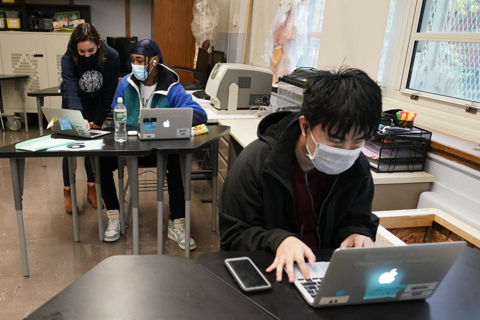 FILE - In this Oct. 29, 2020, file photo, student Tai Nguyen, right, works on his laptop as instructor Chaya Baras, left, helps student Kenny Scottborough, 19, navigate an online lesson at West Brooklyn Community High School in New York. After beginning the year grappling with exasperating delays in their supply chains, the personal computer industry found itself scrambling to keep up with the surging demand for machines that became indispensable during a pandemic that kept millions of workers and students at home. (AP Photo/Kathy Willens, File)