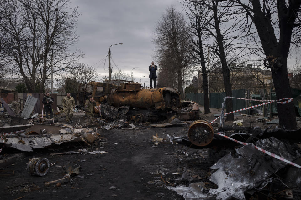 FILE - A journalist stands atop a destroyed vehicle after fights between Russian and Ukrainian forces in Bucha, on the outskirts of Kyiv, Ukraine, April 6, 2022. Ukrainian leaders have encouraged journalists to document what is happening in the country. (AP Photo/Felipe Dana, File)