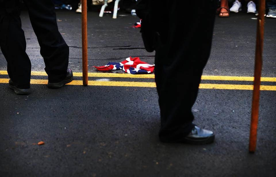 <p>KNA torn up confederate flag lays on the ground beside police as supporters for and against a Fort Sanders Confederate memorial monument face off in Aug. 26, 2017 in Knoxville, Tenn. (Photo: Spencer Platt/Getty Images) </p>