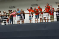 Passengers wave from the MS Westerdam, owned by Holland America Line, docked at the port of Sihanoukville, Cambodia, Friday, Feb. 14, 2020. Hundreds of the cruise ship passengers long stranded at sea by virus fears cheered as they finally disembarked Friday and were welcomed to Cambodia. (AP Photo/Heng Sinith)