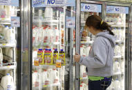 FILE - In this Dec. 4, 2013, file photo Jessica Walton, of Guthrie, Okla., reaches for a container of milk at a grocery store in Edmond, Okla. On Tuesday, Nov. 12, 2019, Dean Foods, the nation's largest milk processor, filed for Chapter 11 bankruptcy protection and said it may sell the company off to the Dairy Farmers of America. (AP Photo/Sue Ogrocki, File)