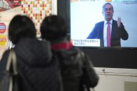 People in Tokyo watch a public TV showing a live broadcast of former Nissan chairman Carlos Ghosn speaking from Lebanon at his press conference Wednesday, Jan. 8, 2020. Ghosn fled to Lebanon from Japan where he is facing charges of financial misconduct, managing to skip bail and leave Japan despite heavy surveillance in Tokyo. (AP Photo/Eugene Hoshiko)