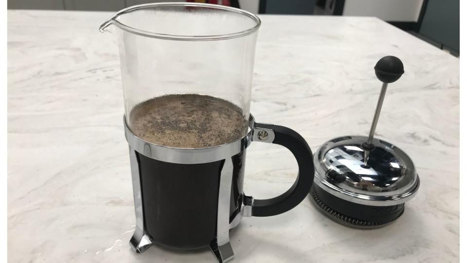 A french press filled with water, but the plunger is off at the side