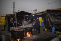 Farmers cook food for fellow farmers in the middle of a major highway which is blocked in a protest against new farm laws at the Delhi-Uttar Pradesh state border, India, Wednesday, Jan. 20, 2021. Farmers have been blockading highways connecting New Delhi to northern India for nearly seven weeks against new farm laws, obstructing transportation and dealing a blow to manufacturing and businesses in the north. Farmers fear the government will stop buying grain at minimum guaranteed prices and that corporations will then push prices down under the new laws. (AP Photo/Altaf Qadri)