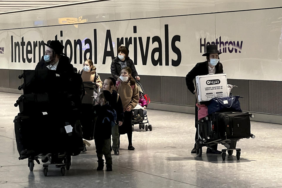 Passengers arrive at Heathrow Airport in London, Monday, Nov. 29, 2021. The new potentially more contagious omicron variant of the coronavirus popped up in more European countries on Saturday, just days after being identified in South Africa, leaving governments around the world scrambling to stop the spread. In Britain, Prime Minister Boris Johnson said mask-wearing in shops and on public transport will be required, starting Tuesday. (AP Photo/Frank Augstein)