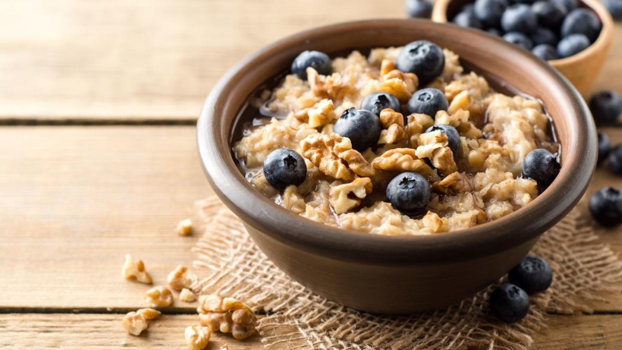 oatmeal porridge with blueberries walnuts and honey in ceramic bowl on wooden background
