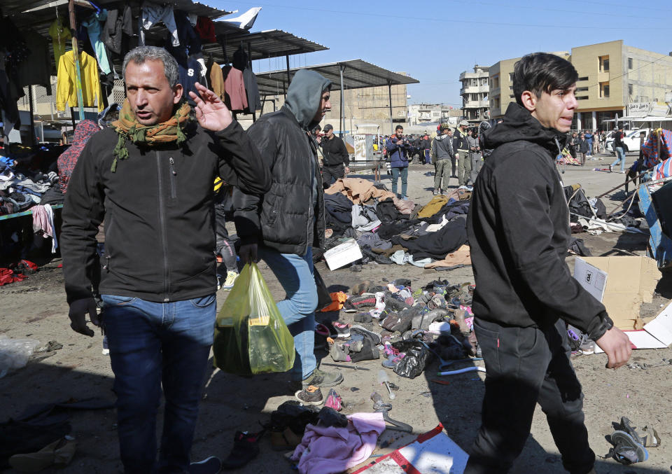 People and security forces gather at the site of a deadly bomb attack in Baghdad, Iraq, Thursday, Jan. 21, 2021. Iraq's military said twin suicide bombings at the Bab al-Sharqi commercial area in central Baghdad Thursday ripped through the busy market killing over two dozen and wounding over 70, with some in serious condition. (AP Photo/Hadi Mizban)