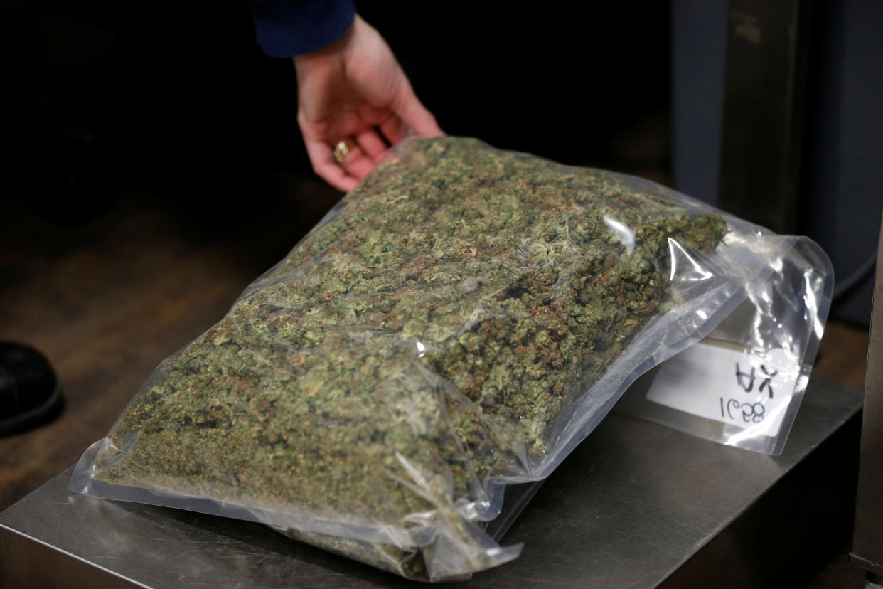 A worker weighs a package of dried marijuana at the Canopy Growth Corporation facility in Smiths Falls, Ontario, Canada, January 4, 2018. Picture taken January 4, 2018. To match Insight CANADA-MARIJUANA/INNOVATION   REUTERS/Chris Wattie