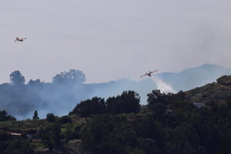 Flames and smoke from a forest fire are seen in the village of Guia.