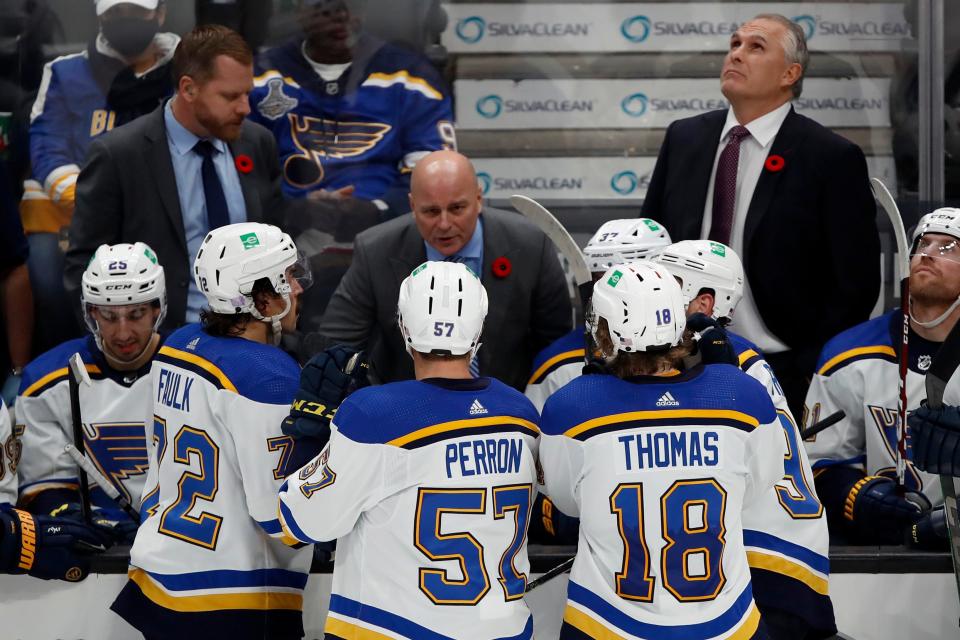 St. Louis Blues assistant coach Jim Montgomery, center, talks to the team, while head coach Craig Berube, right, watches from behind the bench during a game last season.