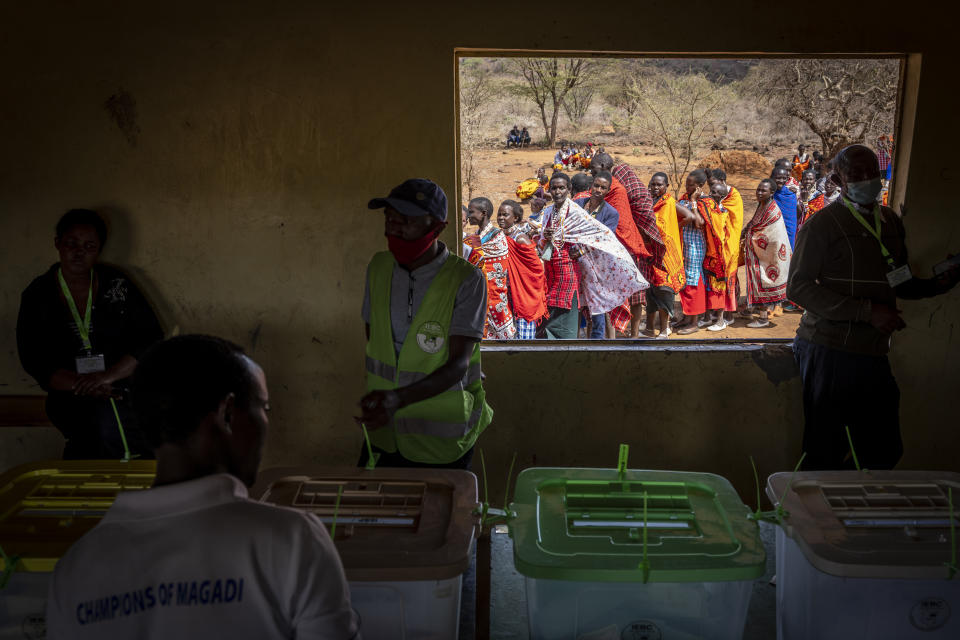 Maasai waiting in line to cast their votes look through an open window at electoral officials inside a polling station at Niserian Primary School, in Kajiado County, Kenya, Tuesday, Aug. 9, 2022. Polls opened Tuesday in Kenya's unusual presidential election, where a longtime opposition leader who is backed by the outgoing president faces the deputy president who styles himself as the outsider. (AP Photo/Ben Curtis)