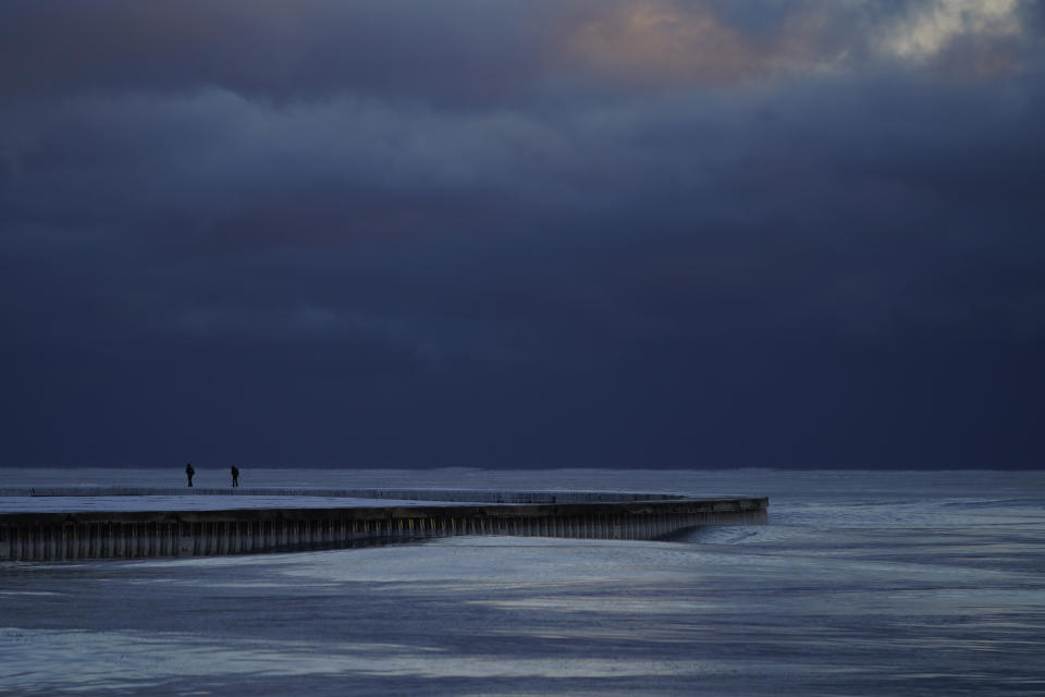 People walk along an icy pier at sunrise near North Avenue Beach Friday, Feb. 3, 2023, in Chicago. (AP Photo/Kiichiro Sato)