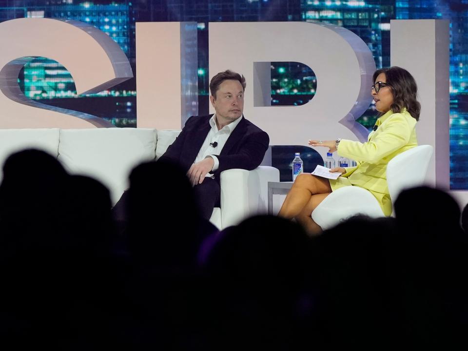 Elon Musk and Linda Yaccarino sit on a stage.