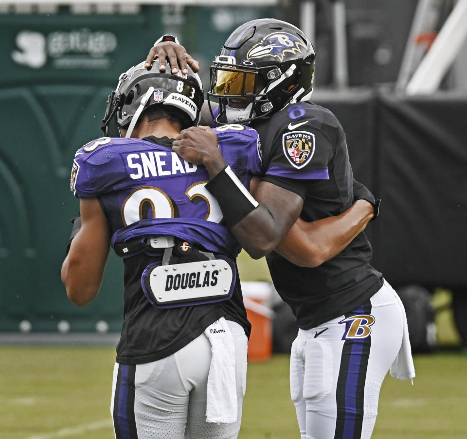 Lamar Jackson hugs Willie Snead IV and pats his helmet during a practice.