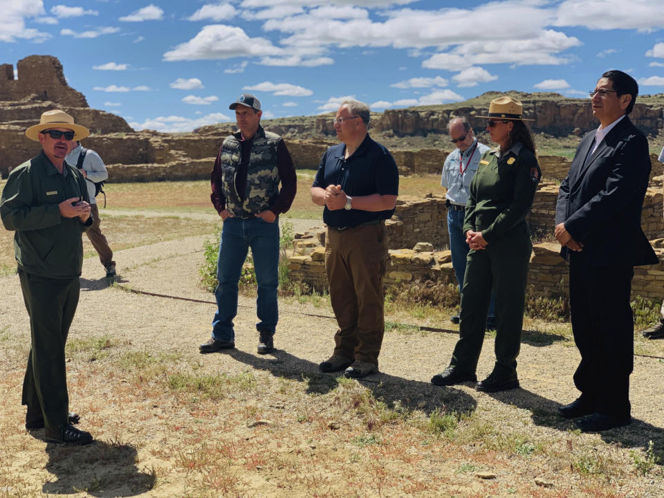 In this photo provided by the Navajo Nation, Interior Secretary David Bernhardt, center, tours Chaco Culture National Historical Park about 95 miles northeast of Gallup, New Mexico, on Tuesday, May 28, 2019. U.S. Sen. Martin Heinrich of New Mexico is at Bernhardt's right. Navajo Nation President Jonathan Nez is on his left. (Jared Touchin/Navajo Nation via AP)